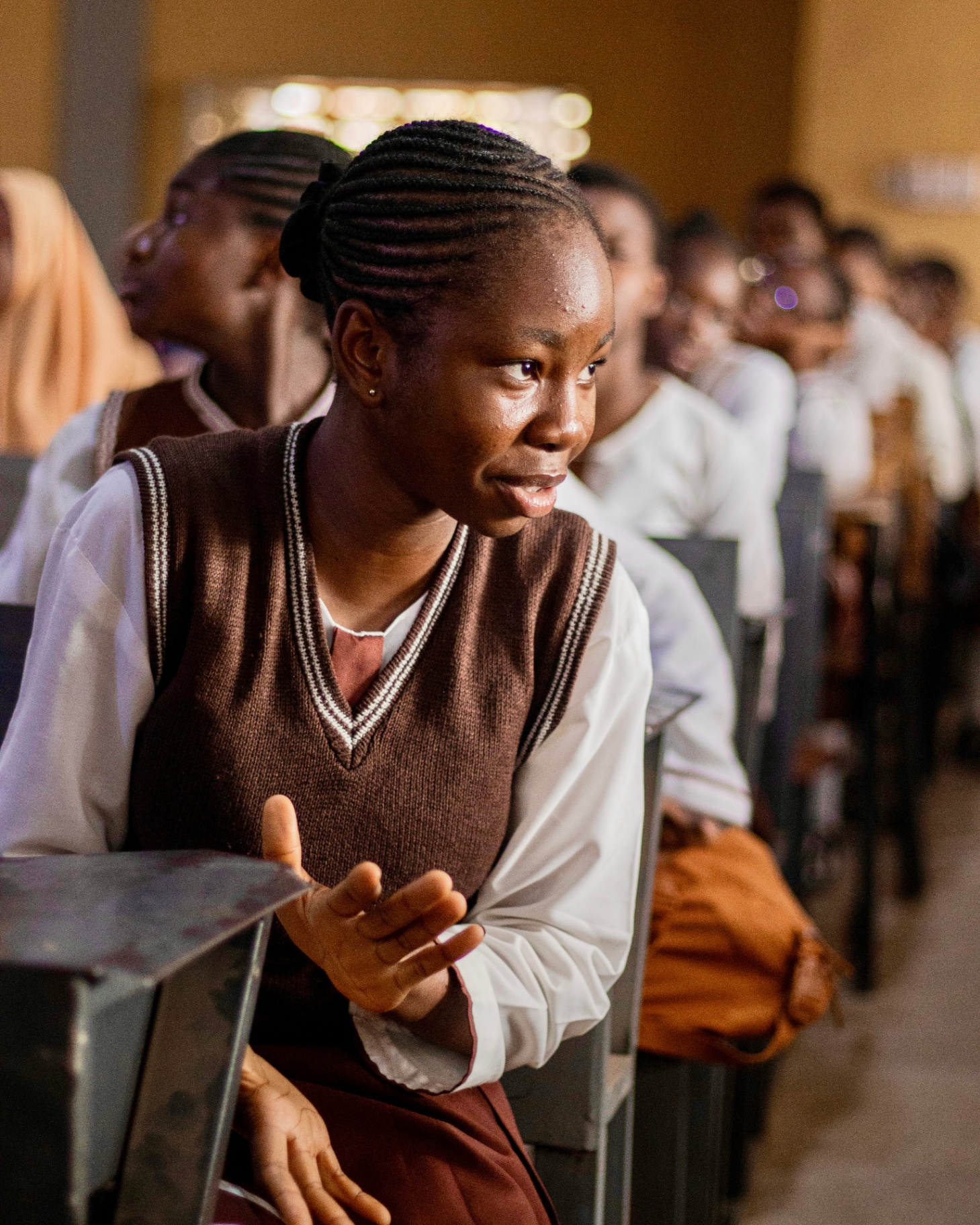 A student in a Nigerian classroom leaning forward, listening intently.